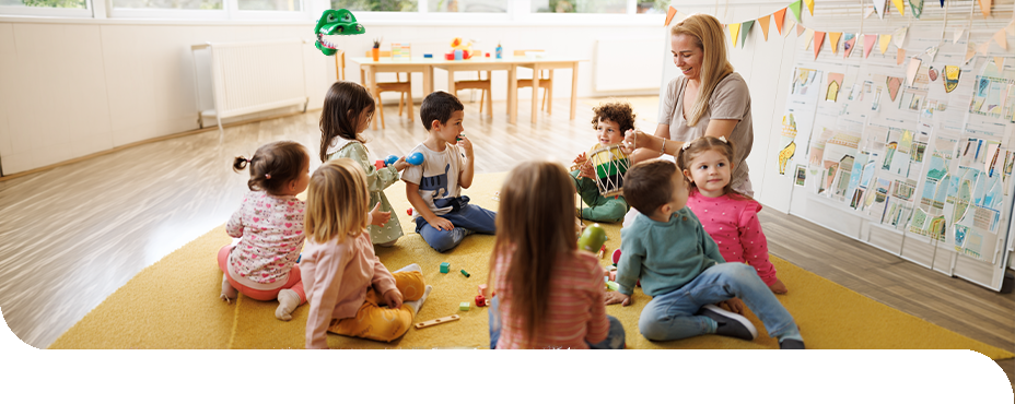 Eine Erzieherin musiziert mit einer Kindergruppe im Morgenkreis und f&ouml;rdert spielerisch Gemeinschaft und Kreativit&auml;t.